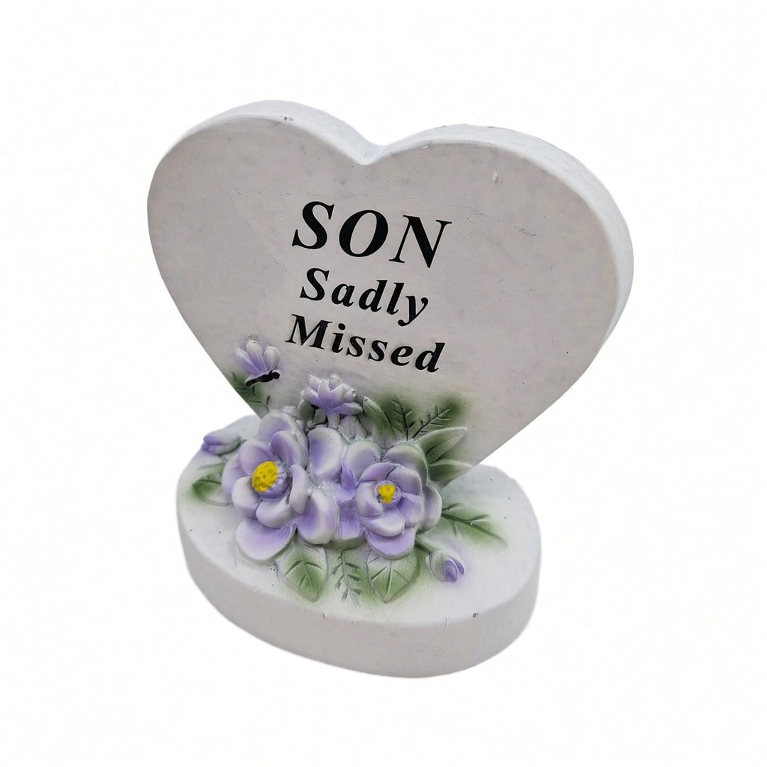 Son Sadly Missed white heart memorial with purple flowers close up
