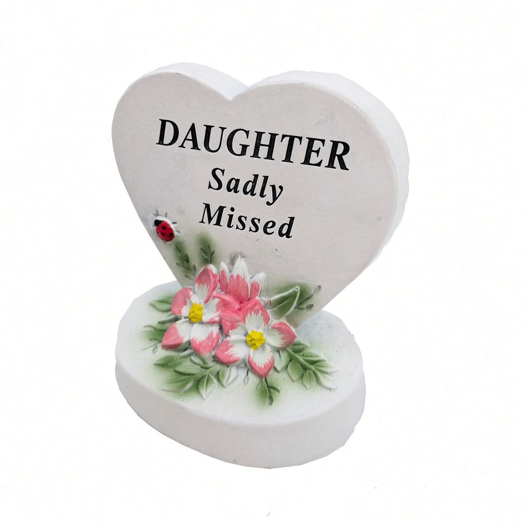 Daughter Sadly Missed white heart memorial with pink flowers close up
