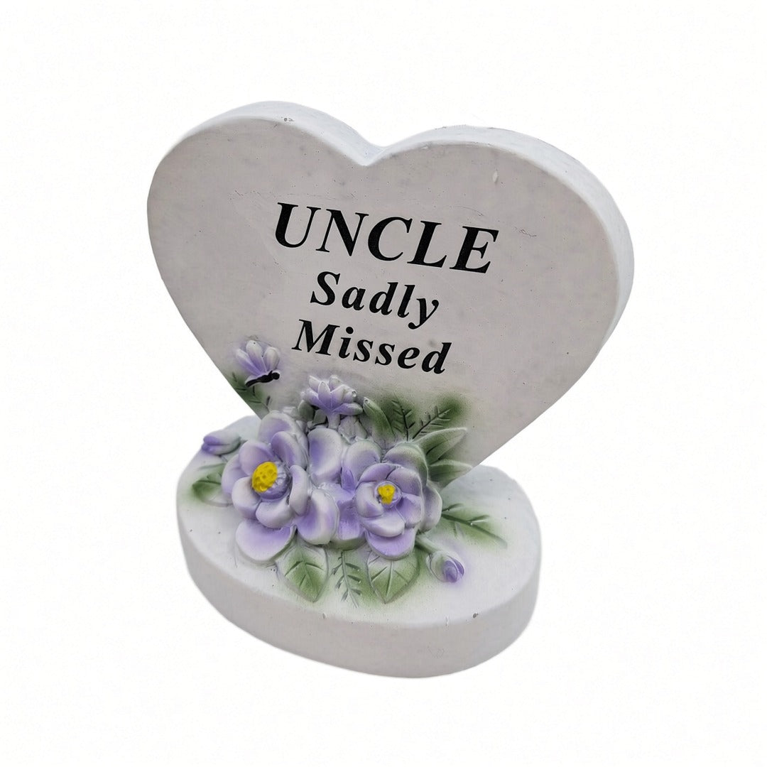 Uncle Sadly Missed white heart memorial with purple flowers close up